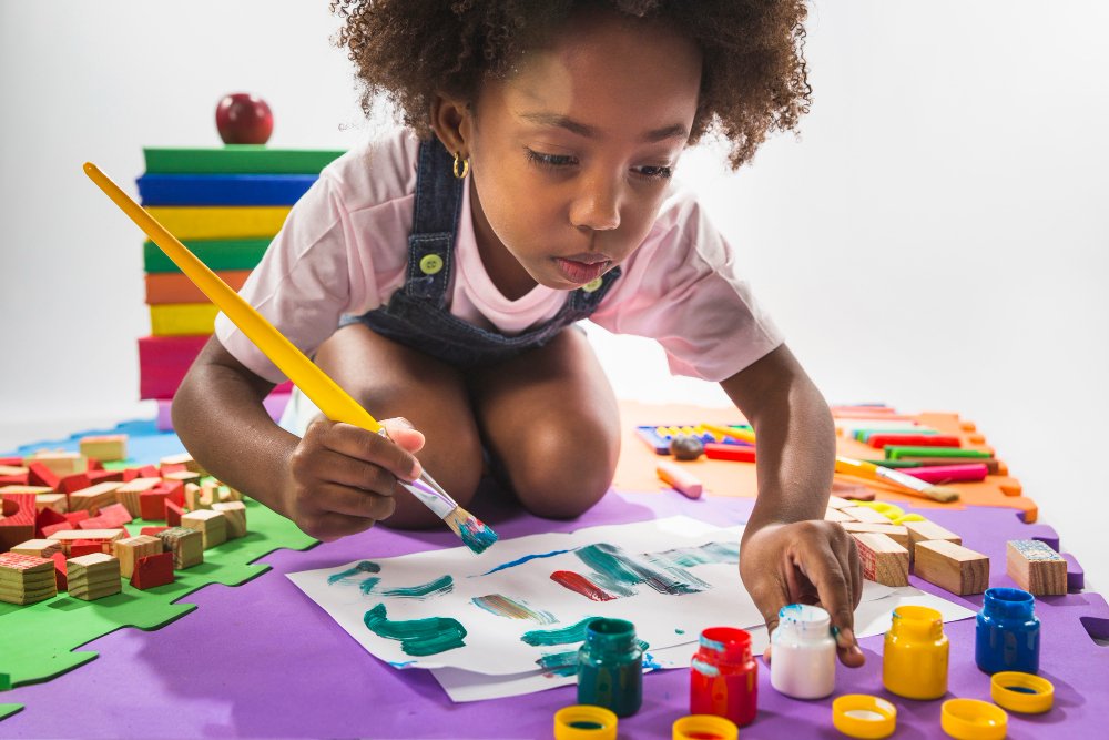 Menina brinca com pintura durante atividade. Na faixa etária entre 3 e 5 anos  as crianças estão prontas para atividades mais complexas que estimulem seu desenvolvimento motor, de comunicação, cognitivo e social